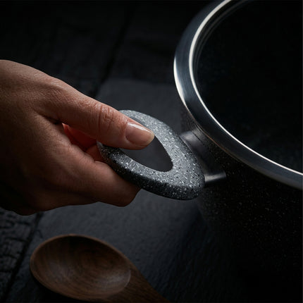 Dettaglio del manico ergonomico con finitura effetto pietra lavica di una pentola Made in Italy.