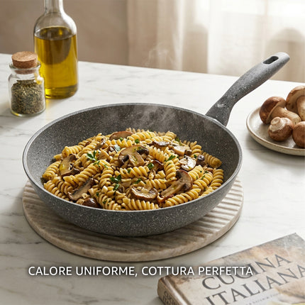 Primo piano di una padella in pietra lavica con pasta saltata per mostrare la cottura uniforme.