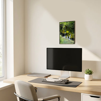 Poster con stampa di un paesaggio naturale appeso sulla parete sopra la scrivania con computer in un ufficio moderno.
